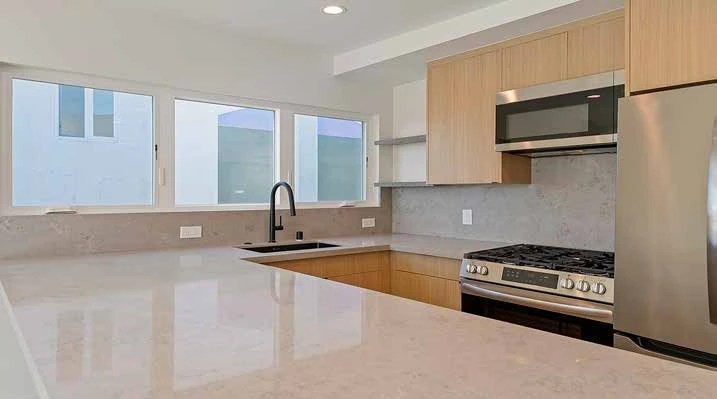 Renovated kitchen with light wood cabinets and stone counters